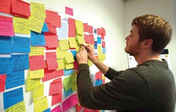 researcher organises post it notes on wall