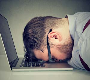stressed worker with face on laptop keyboard