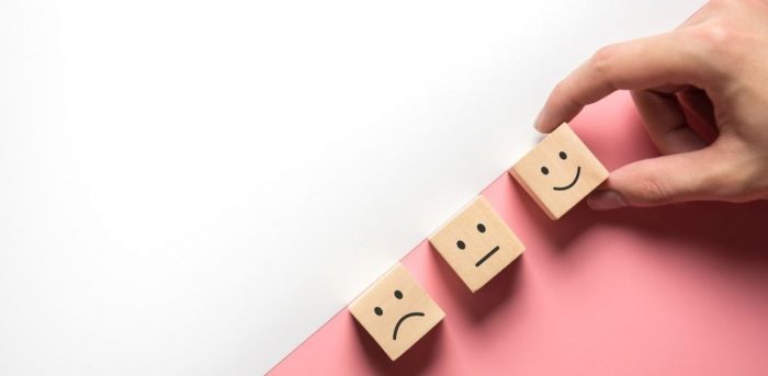 Three wooden blocks showing happy, neutral and sad faces.
