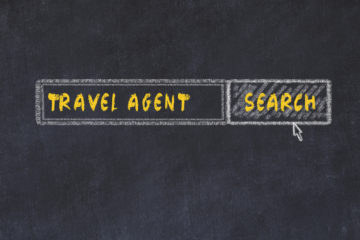 Chalk writing on a blackboard says Travel Agent with a search button.