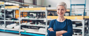 Portrait of a smiling woman standing by industrial racks