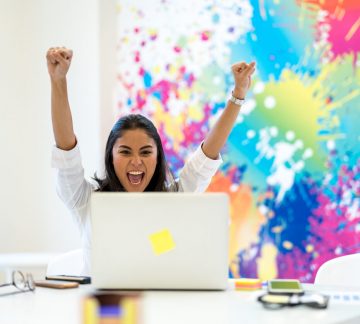 A girl celebrating in a colourful office environment.