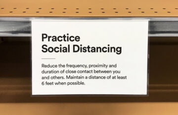 Practice Social Distancing signage, displayed on a empty shelf in supermarket. Asking customers to maintain a distance of at least 6 feet in order to prevent spread of COVID-19.