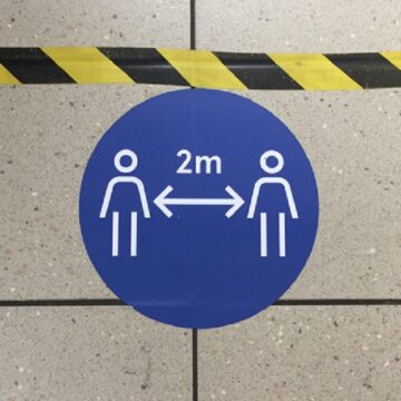 COVID19 social distancing floor signage - blue circle remain 2 meters apart and hazard tape.
