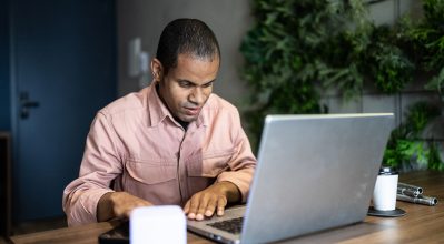 A man with visual impairments using a laptop in an office environment